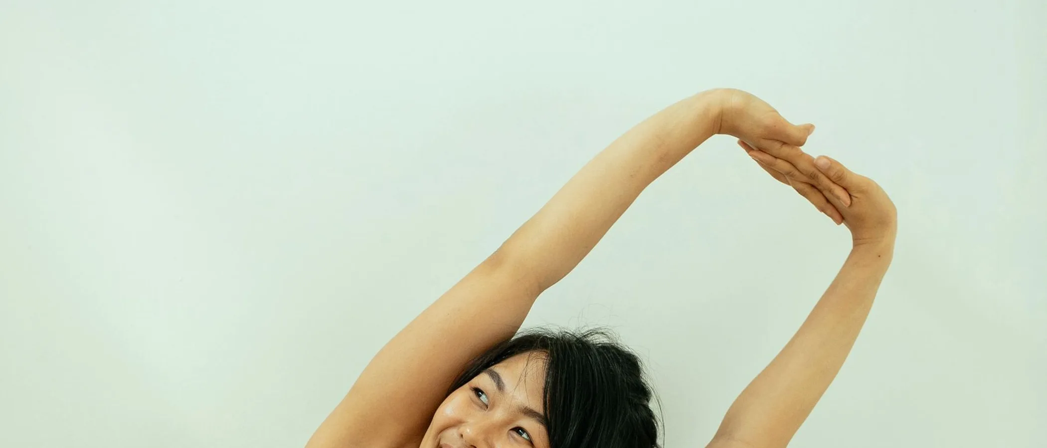 한쪽 팔을 머리 위로 들어 올려 스트레칭하는 사람.