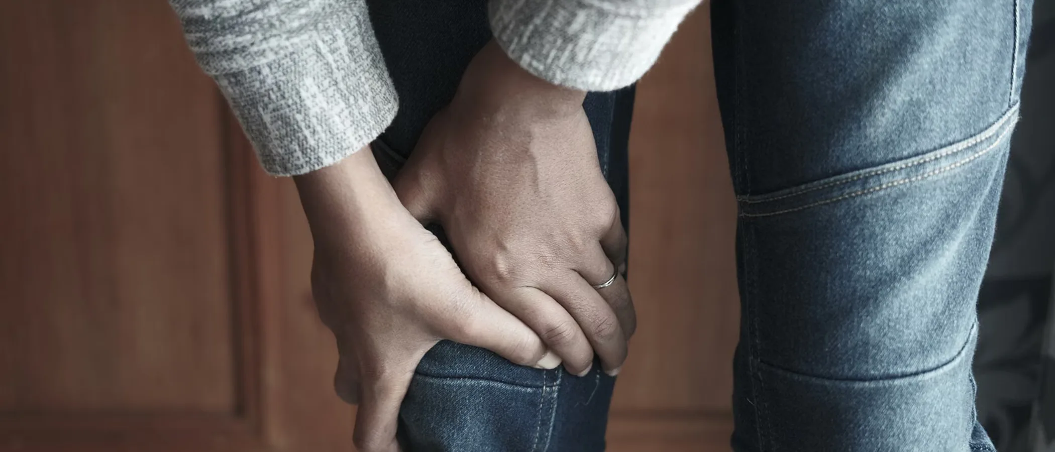 무릎에 두 손을 얹고 있는 사람의 하반신 근접 사진.