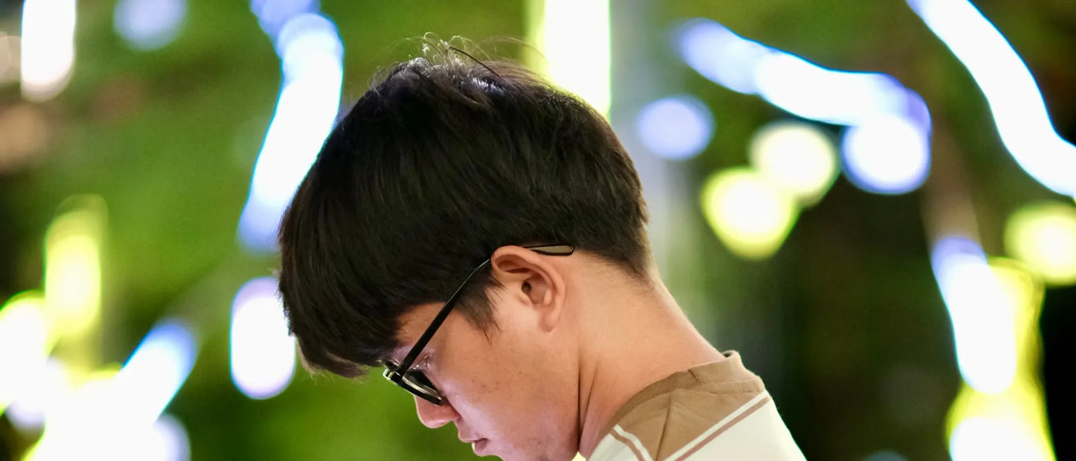 휴대폰을 내려다보는 사람을 옆에서 본 모습. 목의 각도가 드러난다.