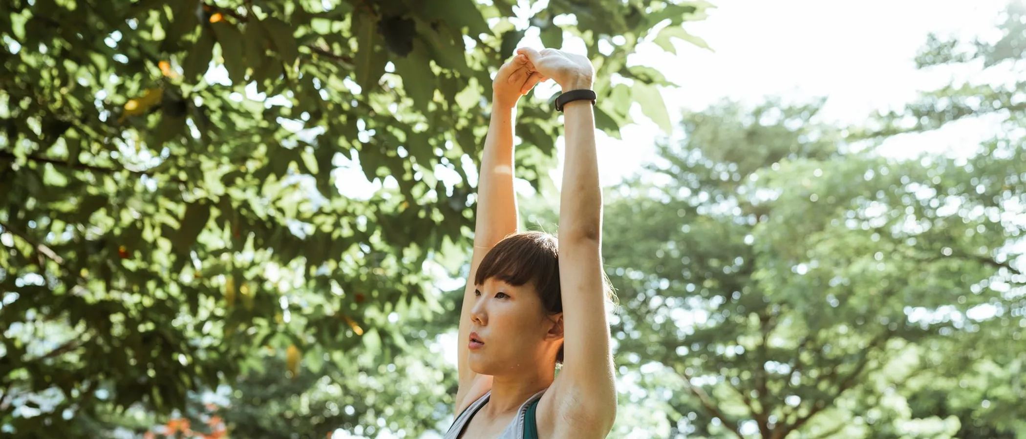 야외에서 두 팔을 머리 위로 뻗는 사람.