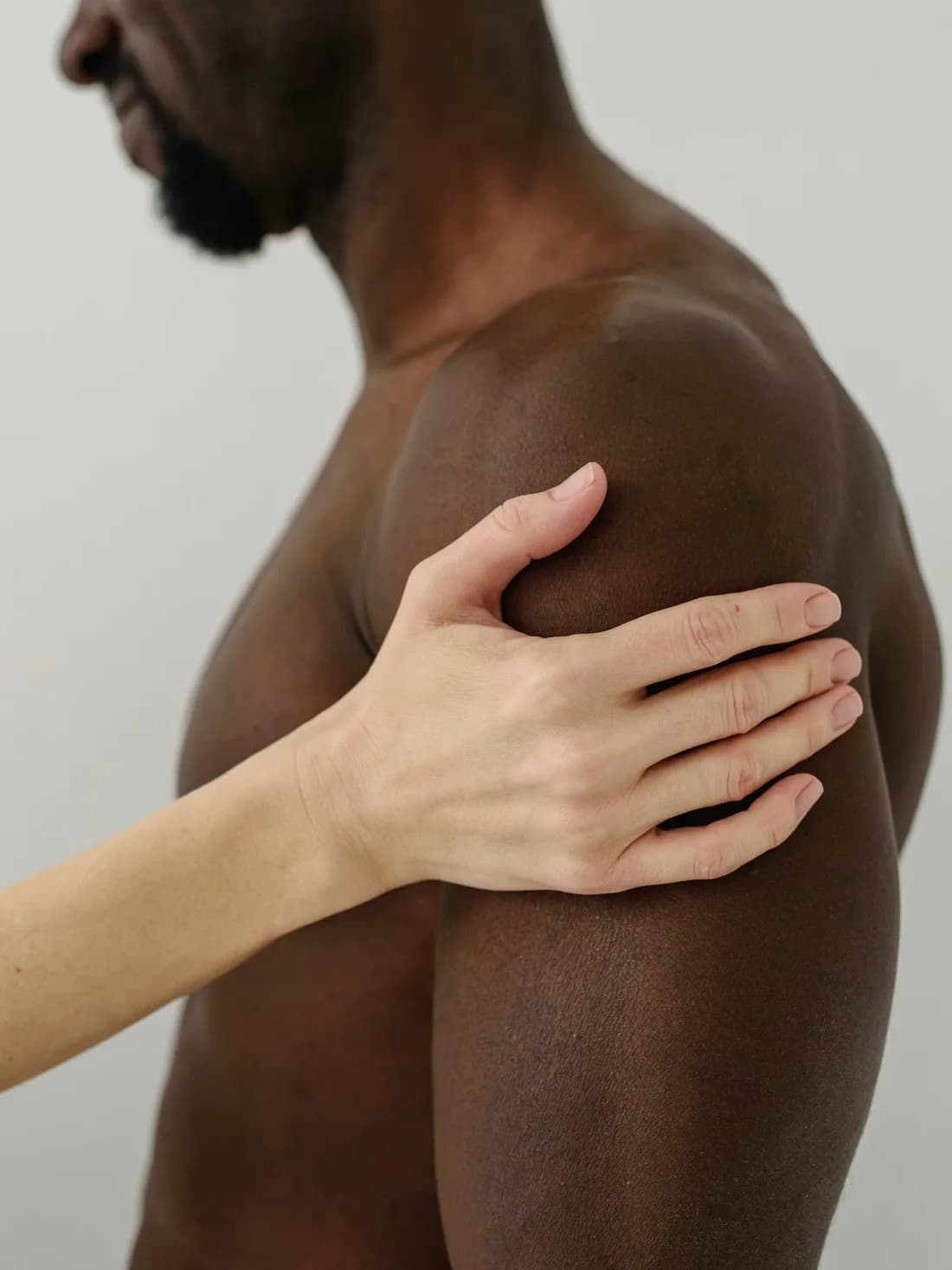 한쪽 어깨를 반대 손으로 감싸 쥔 근접 사진.
