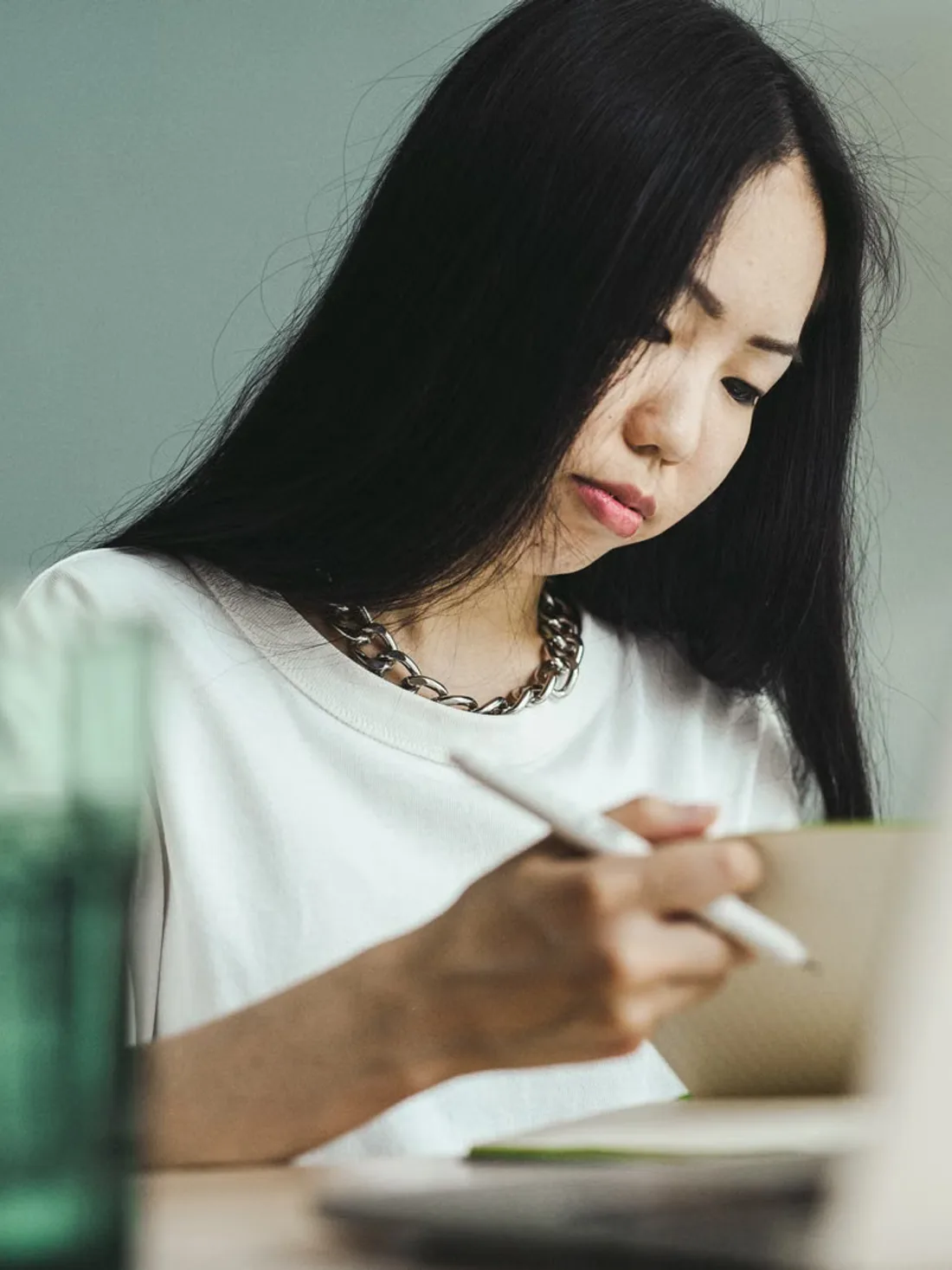 책상에서 고개를 숙이고 무언가를 적는 사람.