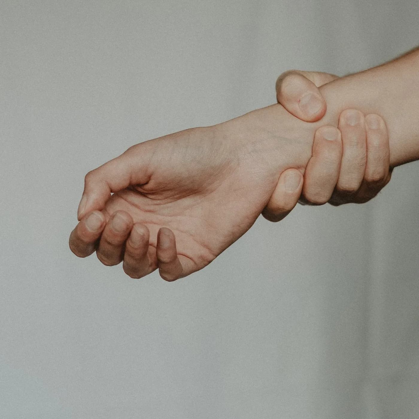 한 손으로 반대 손목을 감싸 쥔 근접 사진.